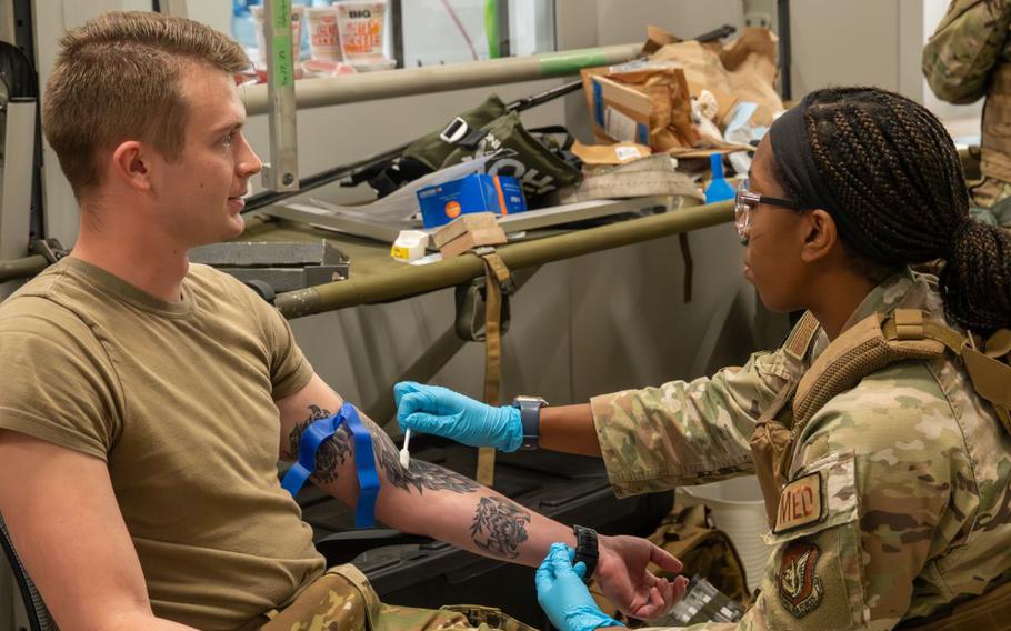 U.S. Air Force Senior Airman Devon Kelsey-Lewis, 18th Civil Engineer Squadron firefighter, left, has his arm swabbed by U.S. Air Force 1st Lt. DarreAuna Morris, 18th Operational Medical Readiness Squadron Project Valkyrie project manager, prior to having his blood drawn during a USAF-led operational exercise Beverly Midnight 26.